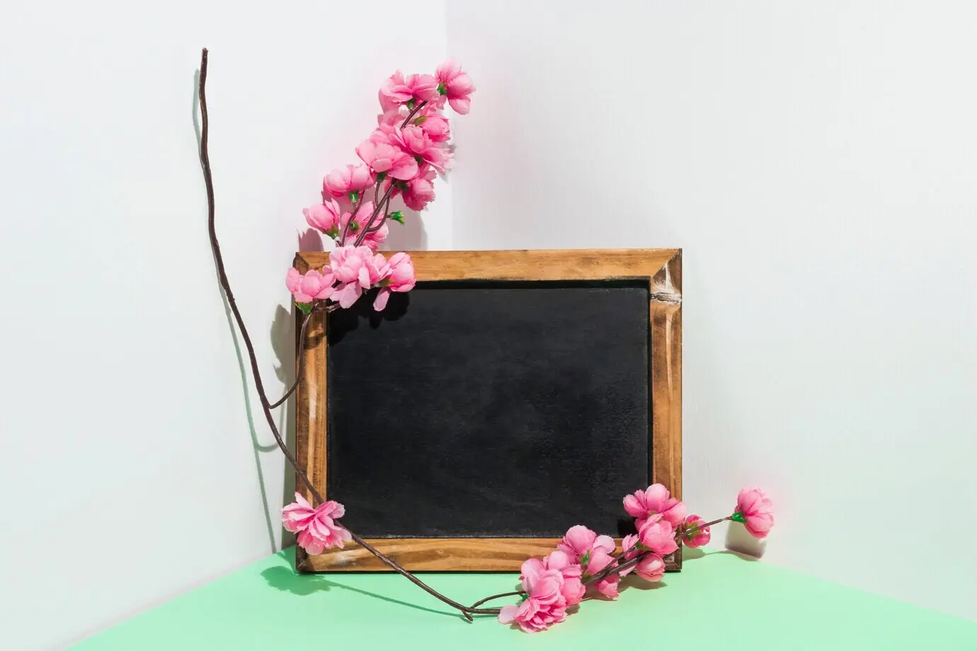 Unbeschriftete Kreidetafel mit einem Blumenzweig auf einem Tisch.