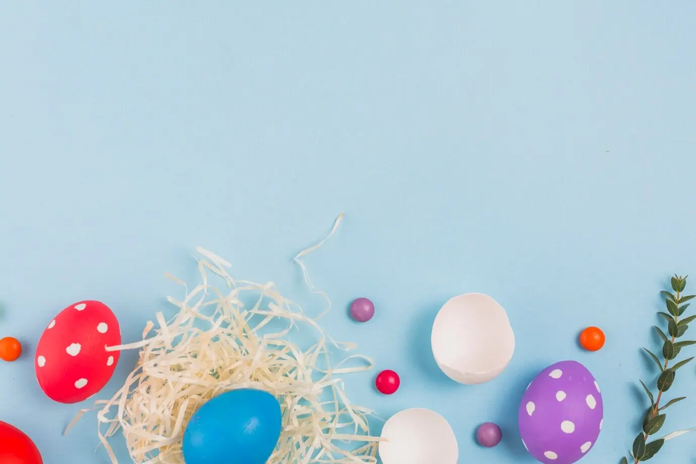 Osterei in einem Nest mit grünem Pflanzenzweig und Süßigkeiten